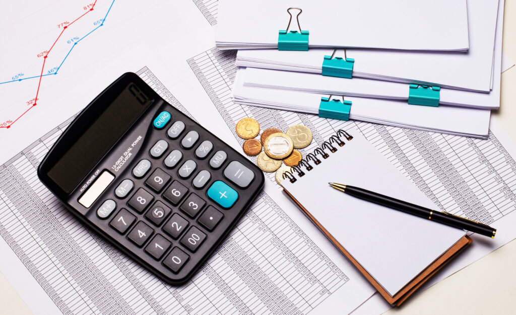 The desktop contains reports, a calculator, a cash register, a notepad and a pen. Business concept. Flat lay