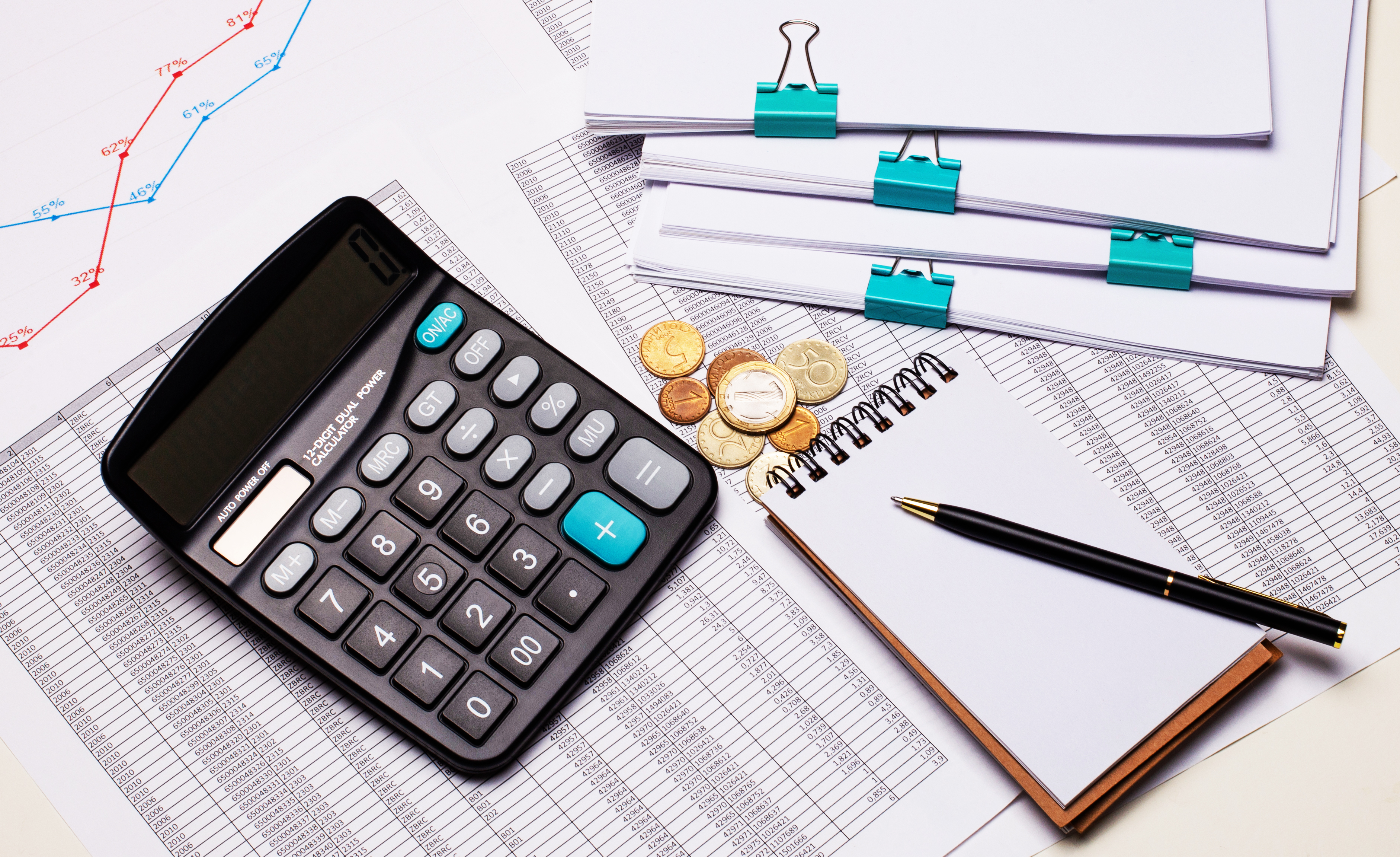 The desktop contains reports, a calculator, a cash register, a notepad and a pen. Business concept. Flat lay